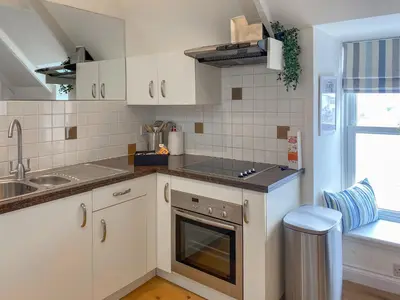 a kitchen with white cabinets and a sink at The Watch House in Saint Mawes