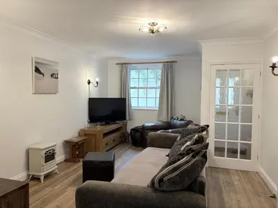 a living room with two couches and a flat screen tv at La Mouette in Mevagissey