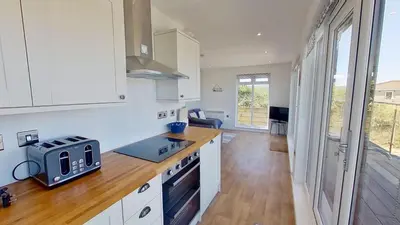 a kitchen with white cabinets and a counter top at D08 Dawn O Day, Riviere Towans in Hayle