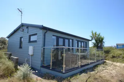 a tiny house with a large deck in a field at D08 Dawn O Day, Riviere Towans in Hayle