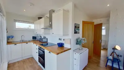 a kitchen with white cabinets and a wooden counter top at D08 Dawn O Day, Riviere Towans in Hayle
