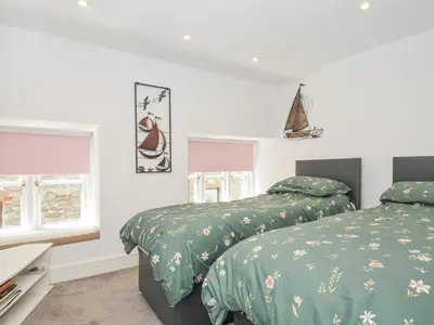two beds in a bedroom with green comforter at Beach Retreat in Looe