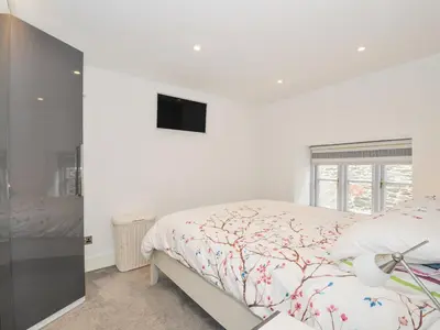 a bedroom with a bed and a tv on the wall at Beach Retreat in Looe