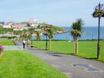 a path with palm trees in a park next to the ocean at Modern surf pad, steps from Towan beach in Newquay