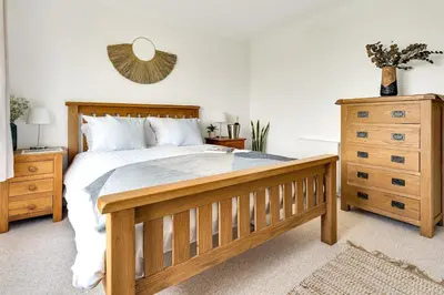 a bedroom with a large wooden bed and a dresser at Cornish house, close to beaches - Ashfield Villas in Falmouth