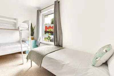 a white bedroom with a bed and a window at Cornish house, close to beaches - Ashfield Villas in Falmouth