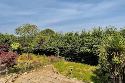 a garden with a fence and trees in the background at Cornish house, close to beaches - Ashfield Villas in Falmouth
