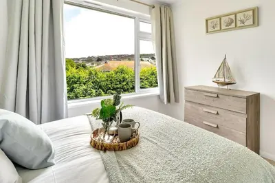 a bedroom with a bed with a large window at Cornish house, close to beaches - Ashfield Villas in Falmouth