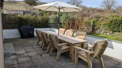 a wooden table with chairs and an umbrella at St Ives Countryside Home with Pool Table & Parking in Towednack