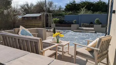 a patio with two chairs and a table with flowers at St Ives Countryside Home with Pool Table & Parking in Towednack