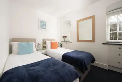 two beds in a room with white walls at Acton Castle in Praa Sands