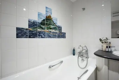 a bathroom with a bath tub and a painting on the wall at Acton Castle in Praa Sands