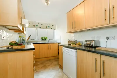 a kitchen with wooden cabinets and a white dishwasher at Beau Vista GF in Padstow