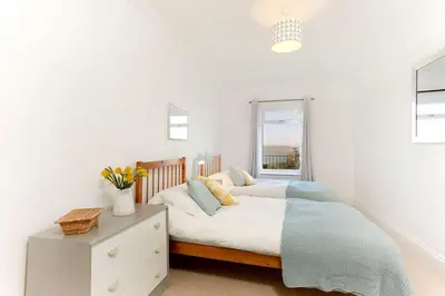 a white bedroom with a bed and a window at Beau Vista GF in Padstow