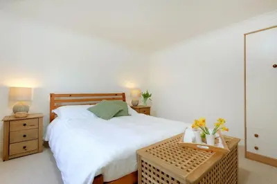 a bedroom with a bed and a table with flowers on it at Beau Vista GF in Padstow