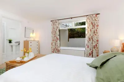 a white bedroom with a large bed and a window at Beau Vista GF in Padstow