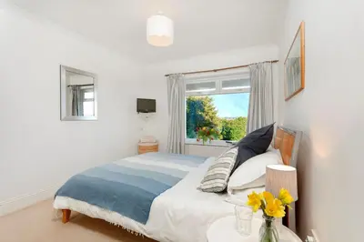 a bedroom with a bed and a window and a table at Beau Vista GF in Padstow