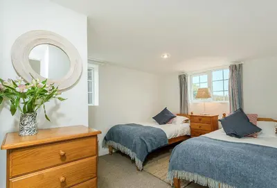 a bedroom with two beds and a mirror at Arnold Cottage in St Merryn