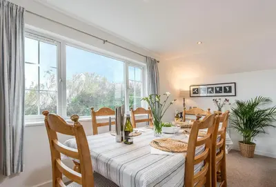 a dining room with a table and a large window at Arnold Cottage in St Merryn