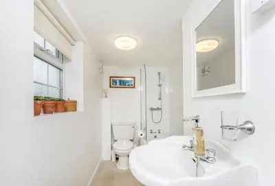 a white bathroom with a sink and a toilet at Arnold Cottage in St Merryn