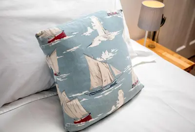 a pillow with a painting of a ship on a bed at Bay View in Port Isaac