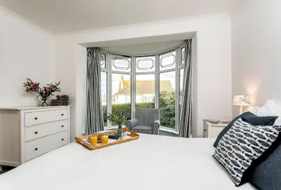 a bedroom with a white bed and a large window at Bay View in Port Isaac