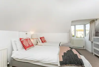 a bedroom with a large white bed with red pillows at Bay View in Port Isaac