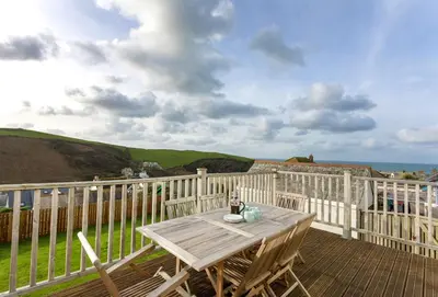 a wooden deck with a table and chairs on a balcony at Bay View in Port Isaac