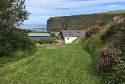 a house on the side of a hill with the ocean at Lower Hillcott in Bude