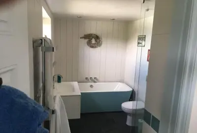 a bathroom with a blue tub and a toilet at Lower Hillcott in Bude