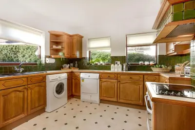 a kitchen with wooden cabinets and a washer and dryer at Beau Vista FF in Padstow