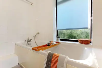 a white bathroom with a tub and a window at Beau Vista FF in Padstow