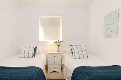 two twin beds in a room with white walls at Beau Vista FF in Padstow