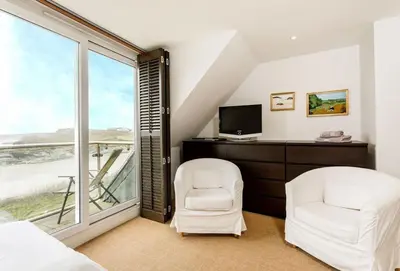a bedroom with two white chairs and a television at Surfside in Newquay
