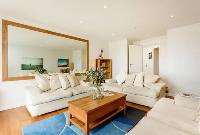 a living room with two white couches and a table at Surfside in Newquay
