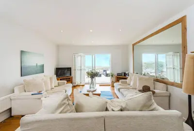 a living room with white couches and a large mirror at Surfside in Newquay
