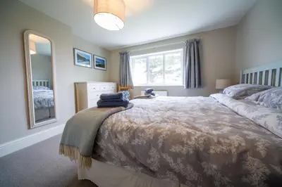 a bedroom with a bed and a large window at Penrose Cottage in Bude
