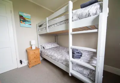 a bedroom with two bunk beds and a night stand at Penrose Cottage in Bude