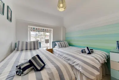 two beds in a room with striped walls at Quayside in Fowey