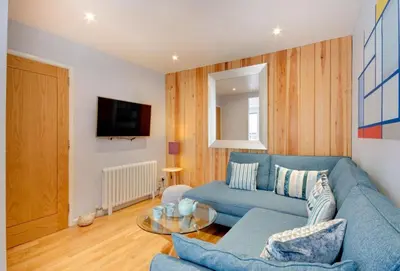 a living room with a blue couch and a table at Quayside in Fowey