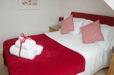 a white bed with red and white towels on it at The Treyarnon Suite in St Merryn