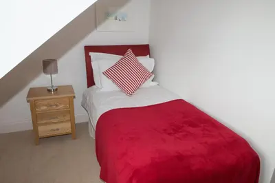 a bedroom with a bed with a red blanket at The Treyarnon Suite in St Merryn