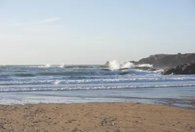 a sandy beach with waves in the ocean at The Treyarnon Suite in St Merryn