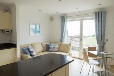 a kitchen and living room with a couch and a table at The Treyarnon Suite in St Merryn
