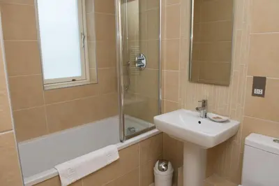 a bathroom with a shower and a sink and a tub at The Treyarnon Suite in St Merryn