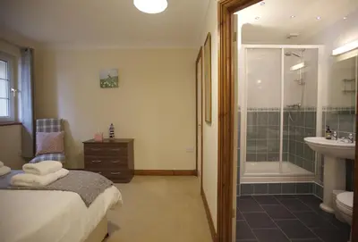 a bathroom with a bed and a shower and a sink at Woodlands in Newquay