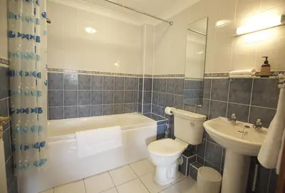 a bathroom with a tub and a toilet and a sink at Woodlands in Newquay
