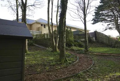 a yard with a fence and a house at Woodlands in Newquay