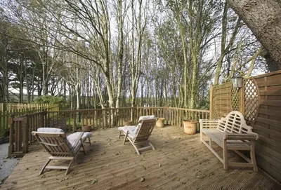 a wooden deck with chairs and a bench on it at Woodlands in Newquay