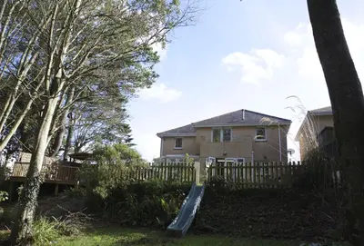 a house with a slide in front of a fence at Woodlands in Newquay